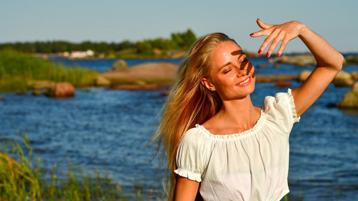 A woman enjoys a sunny day by the rocky beach in Helsinki, Finland, embracing the summer vibes.